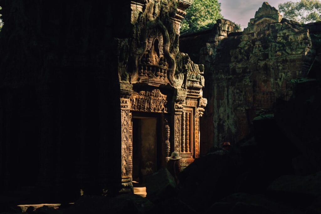 An ancient stone doorway and carved ruins illuminated by morning light at Ta Prohm Temple in Siem Reap