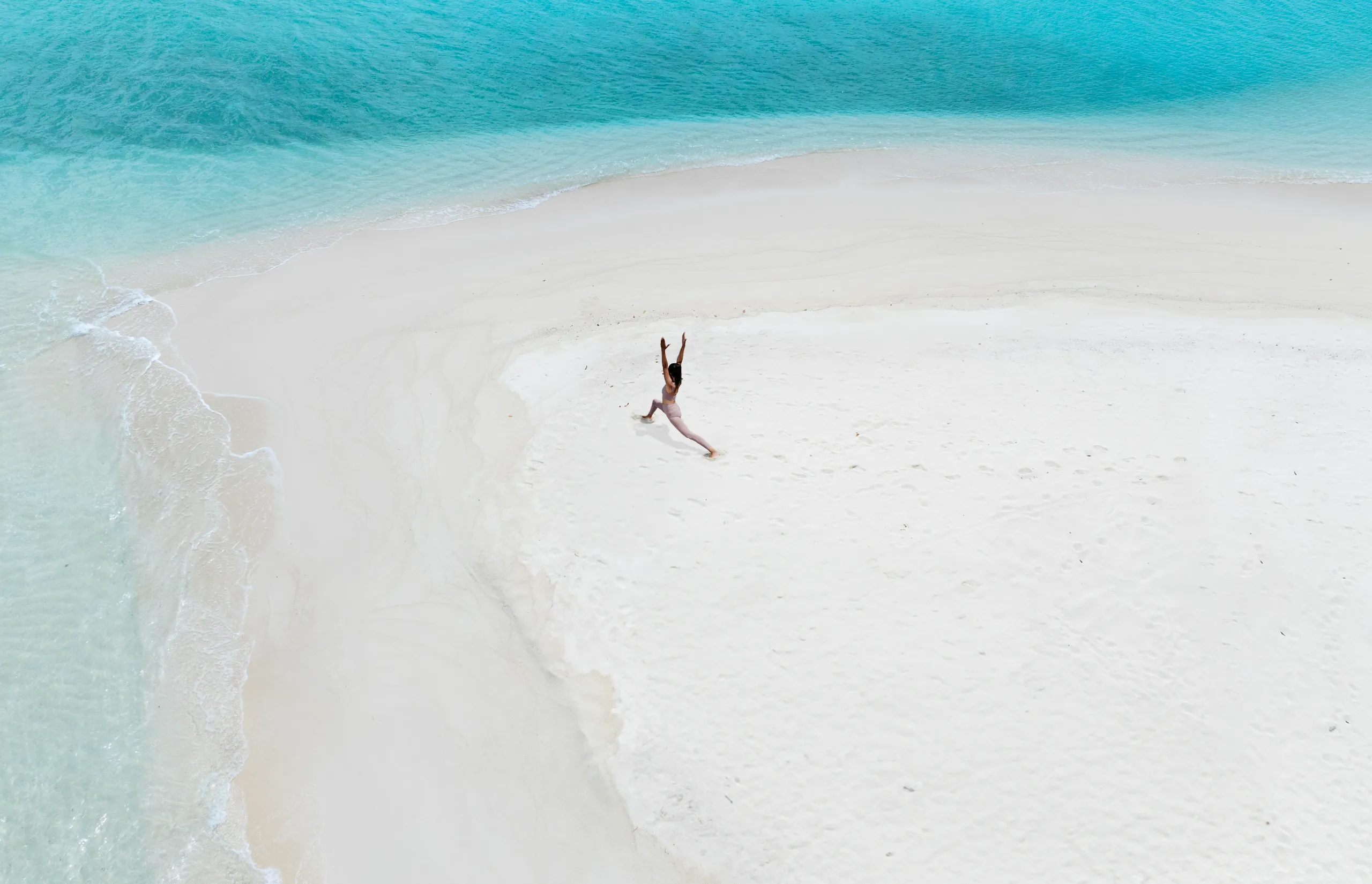 Authentic experiences - female pink yoga clothing aerial view standing yoga pose sandbank boathouse beach