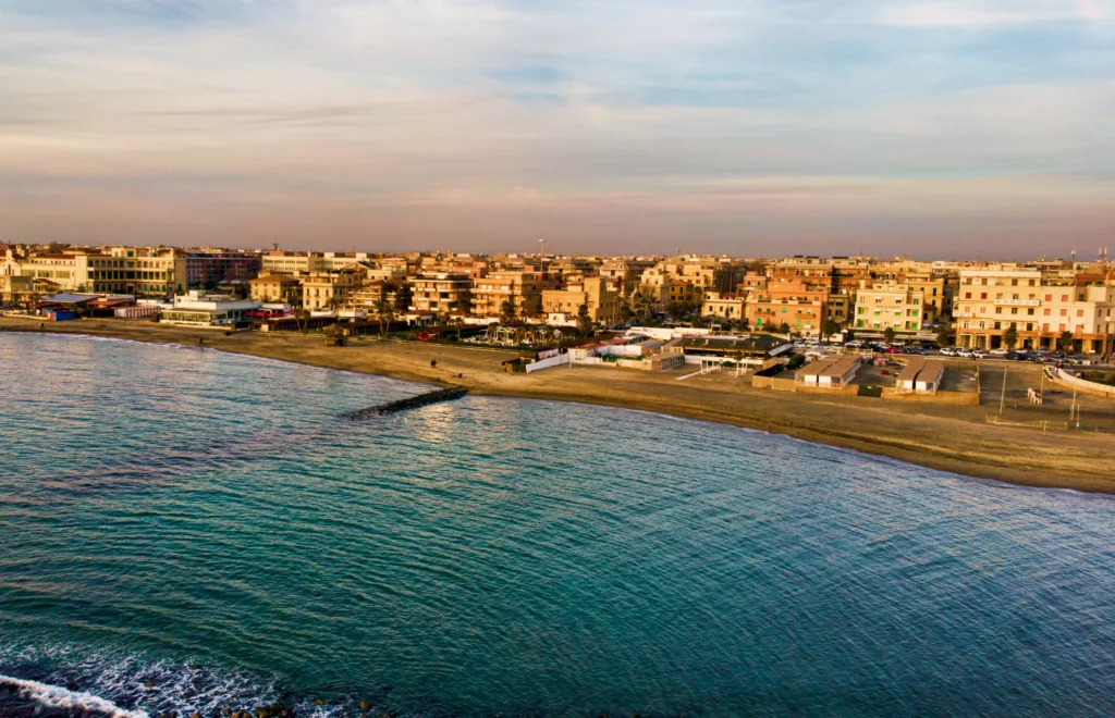 Sunset Rome aerial view in Ostia Lido beach over blue sea and brown sand beach, beautiful coast line and promenade a landmark of tourist and city life