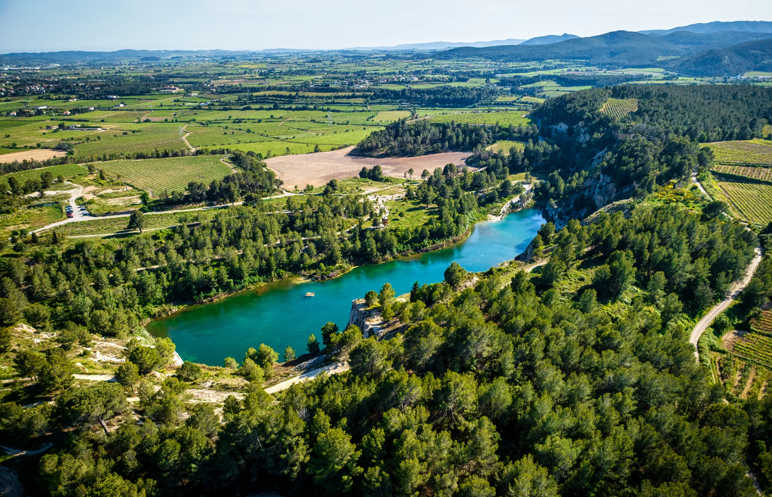 Grand Tour of Catalonia | Aerial view of the stunning Vilovi Lakes, nestled amidst the vineyards and forests of the Penedès region in Catalonia, Spain, creating a picturesque landscape under the summer sun