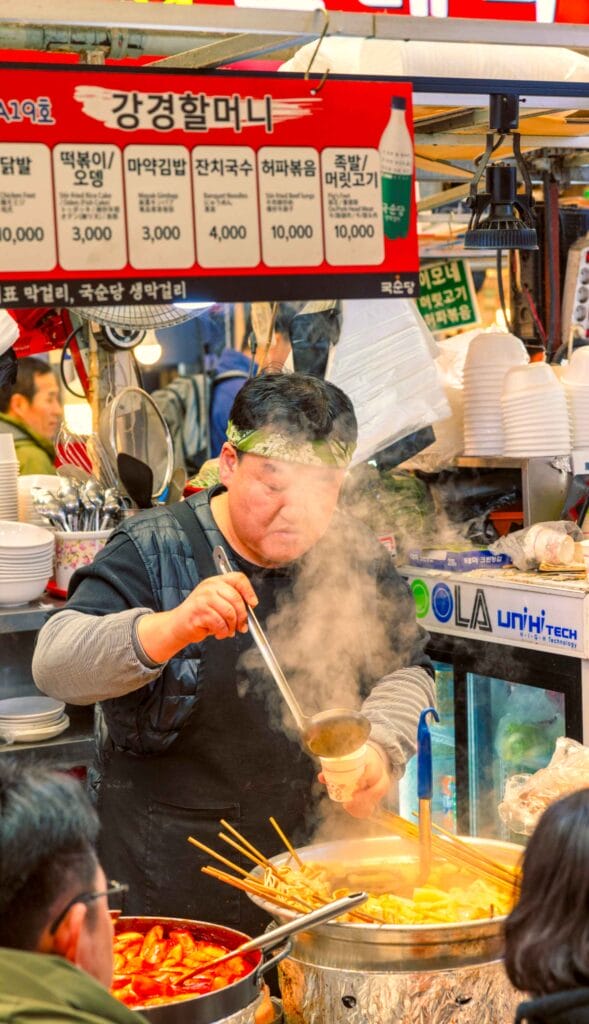 Vendor serving hot street food at Gwangjang Market in Seoul | Seoul city guide