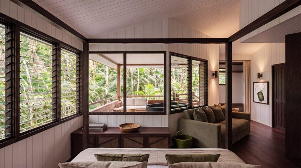 Cabin interior at Ever Bloomfield with louvred windows opening to outdoor bath deck and rainforest