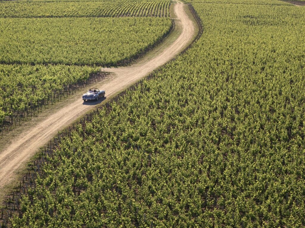 Aerial view of COMO Cordeillan-Bages with classic car and surrounding Médoc vineyard
