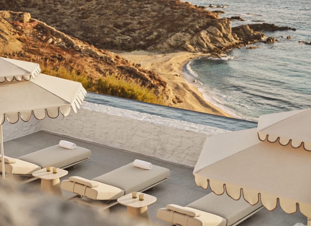 Private beach terrace at Four Seasons Hotel Mykonos with scalloped umbrellas, sun loungers and rocky Aegean coastline