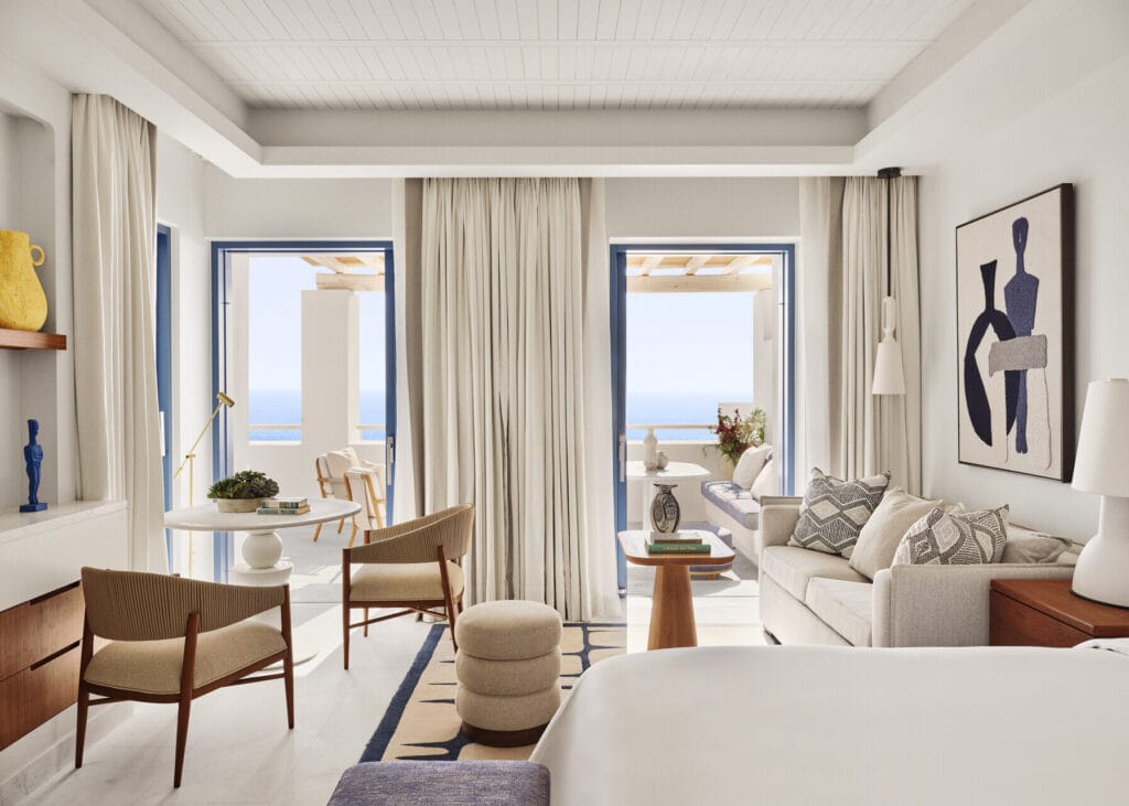 Suite interior at Four Seasons Hotel Mykonos with elegant living area in neutral tones and balcony doors to sea views