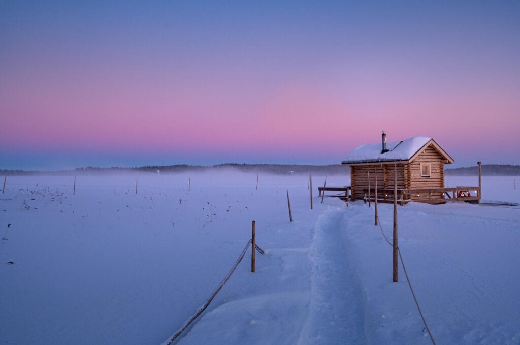 Traditional wooden sauna hut situated on a frozen lake in Finland