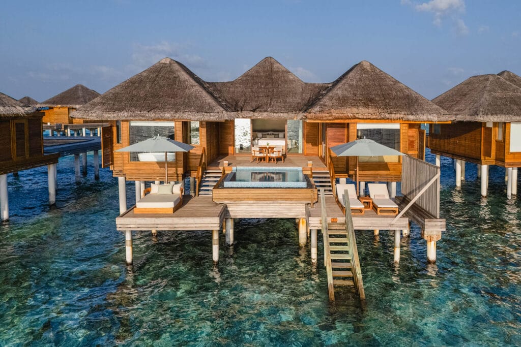 Thatched-roof overwater villa with a personal freshwater pool suspended above the lagoon at Huvafen Fushi resort