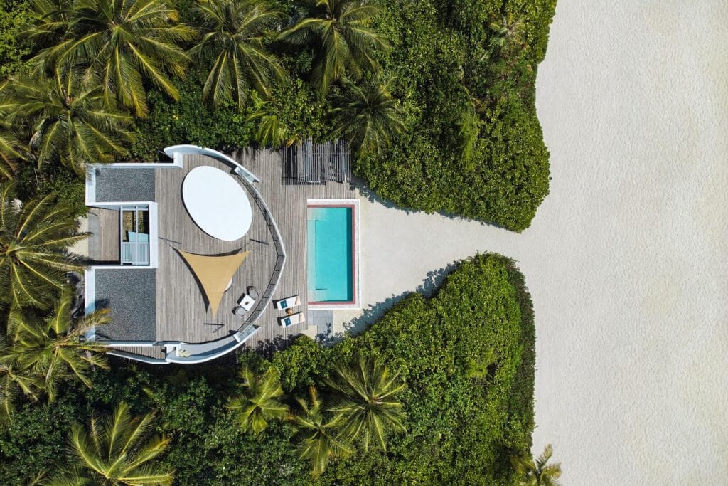 Aerial view of a private beach residence at Jumeirah Maldives Olhahali Island, showcasing a sleek infinity pool and modern design