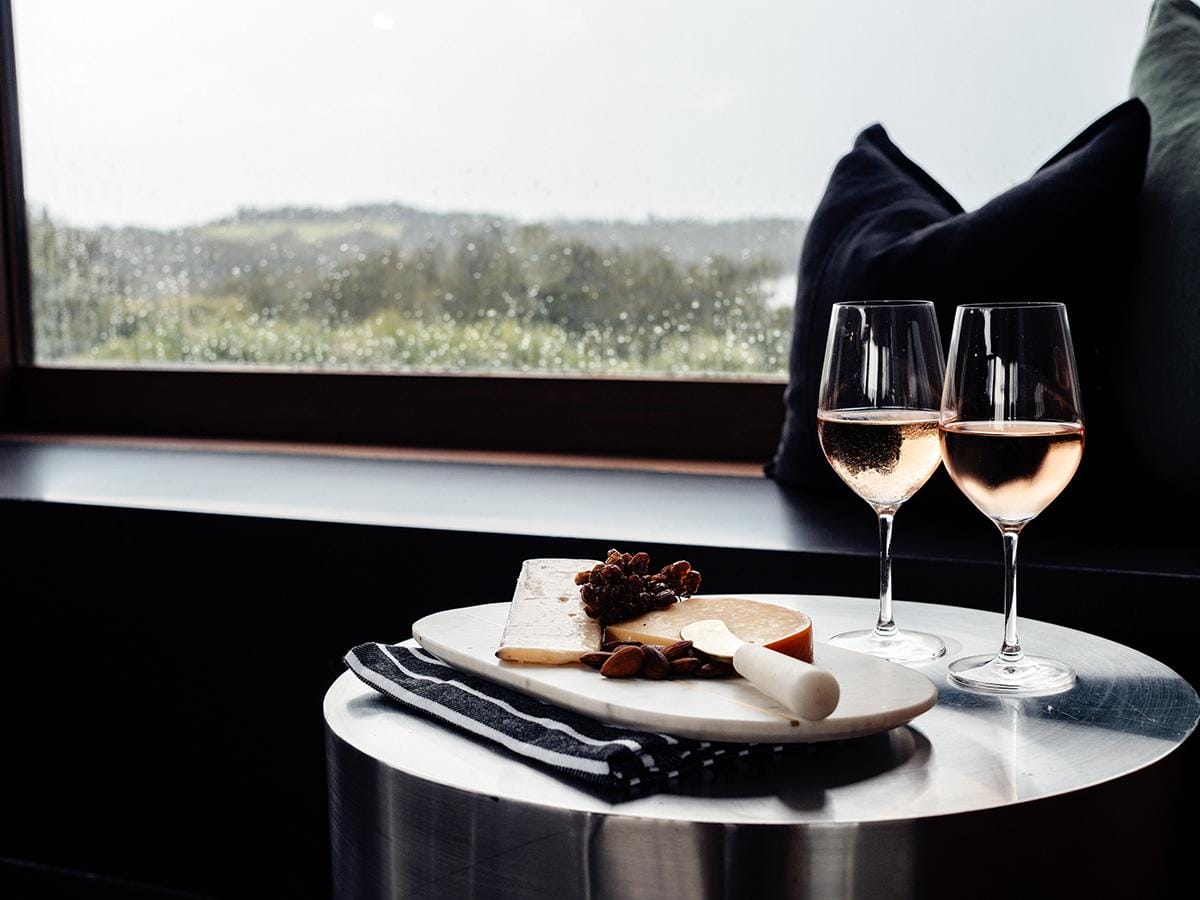 Cheese board and two glasses of champagne by a scenic window at Somnium at Bingie