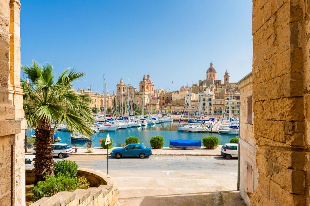 Sunny waterfront view shows the historic harbor and marina in Senglea, one of the famous Three Cities located across the Grand Harbour from Valletta