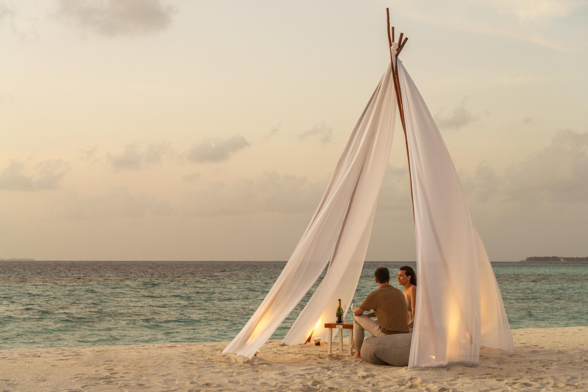 A private romantic beach setup with a white fabric teepee at Constance Hotels & Resorts