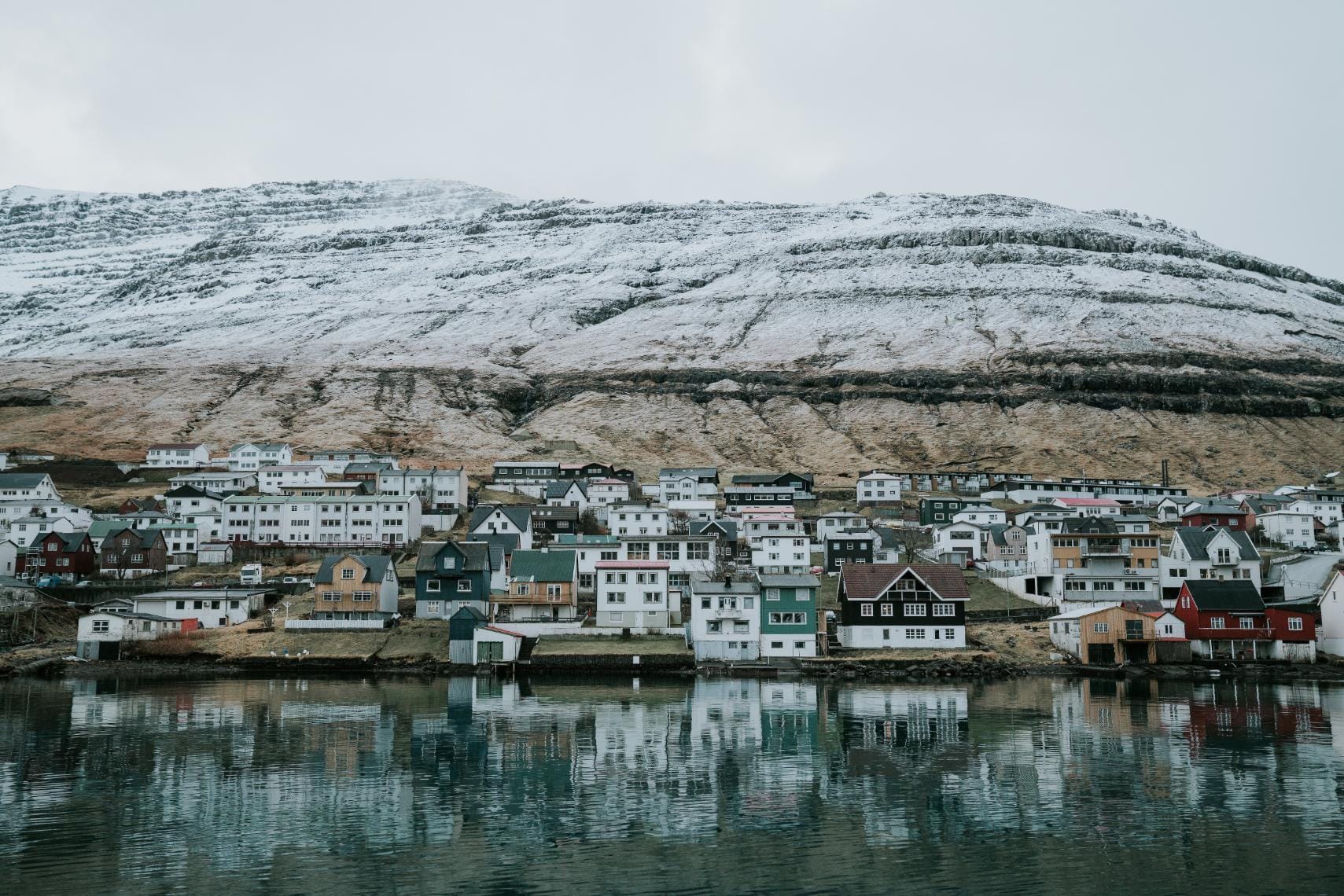The town of Klaksvík nestled along the water in the Faroe Islands, framed by snow-dusted mountains