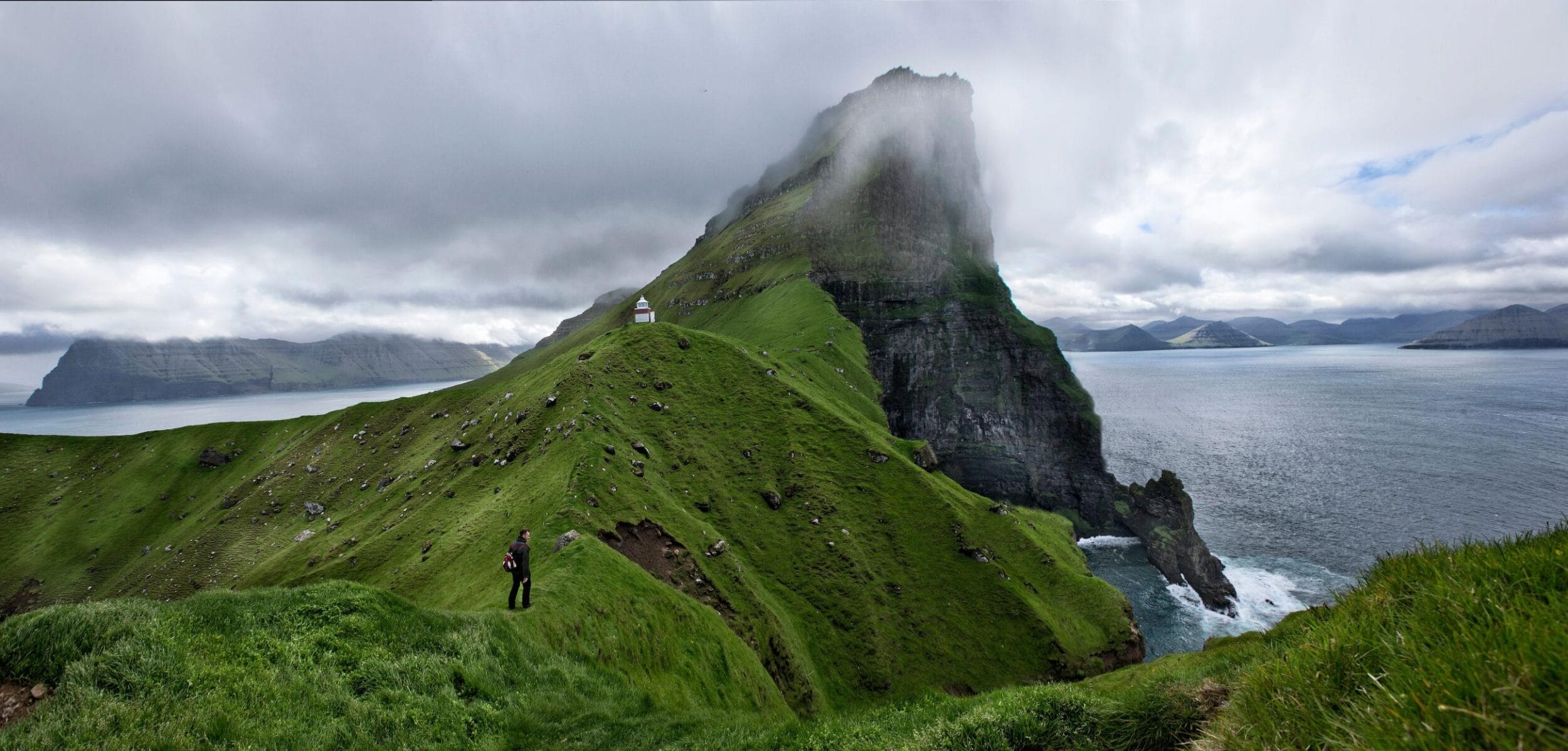 Green ridge and cliffs leading to the Kallur Lighthouse on the northern tip of Kalsoy Island